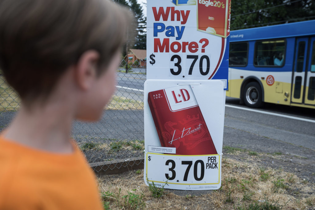 Child looking at tobacco advertisements outside of a convenience store