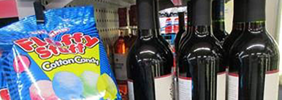 Close up of wine being sold immediately next to fluffy stuff cotton candy inside a store