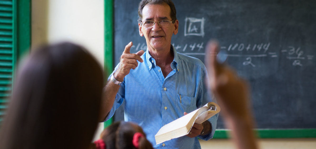 Older teacher answering a student's question in the classroom
