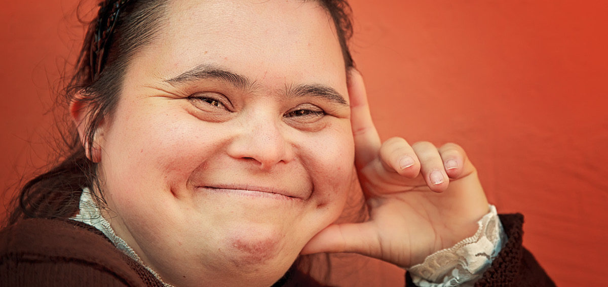 Woman living with disability smiling at camera with hand on face