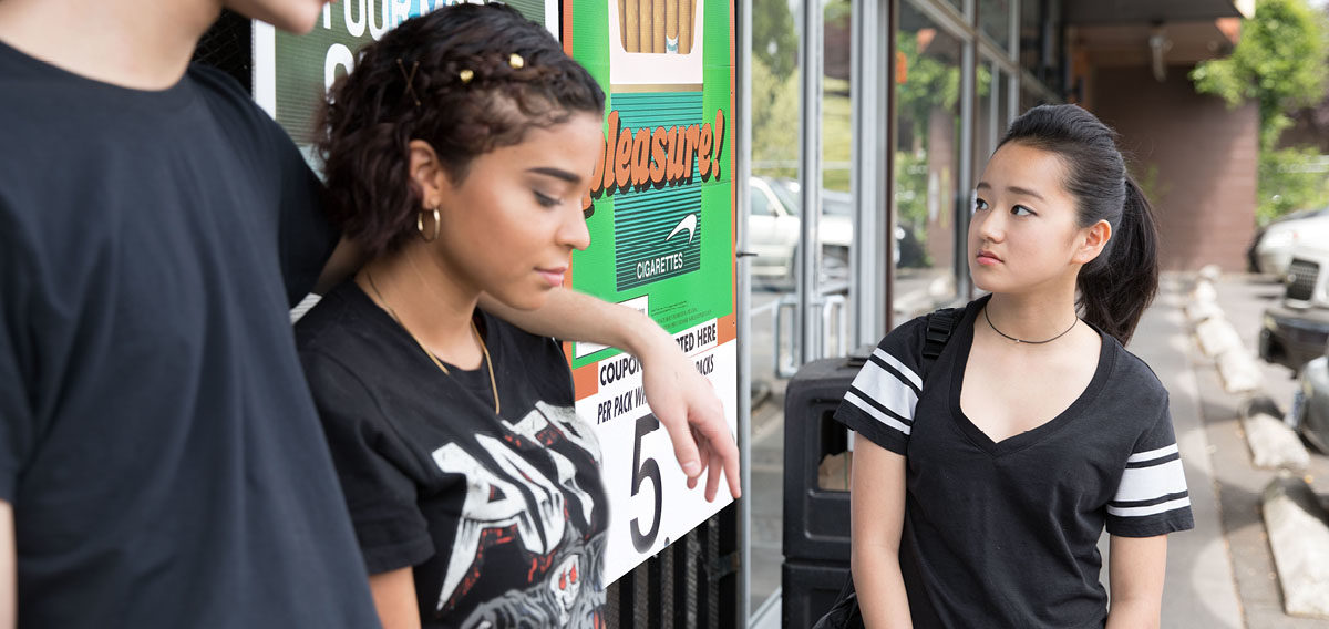 Teens outside convenience store, one staring at tobacco ads