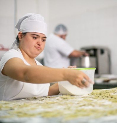Younger female living with a disability working making pasta