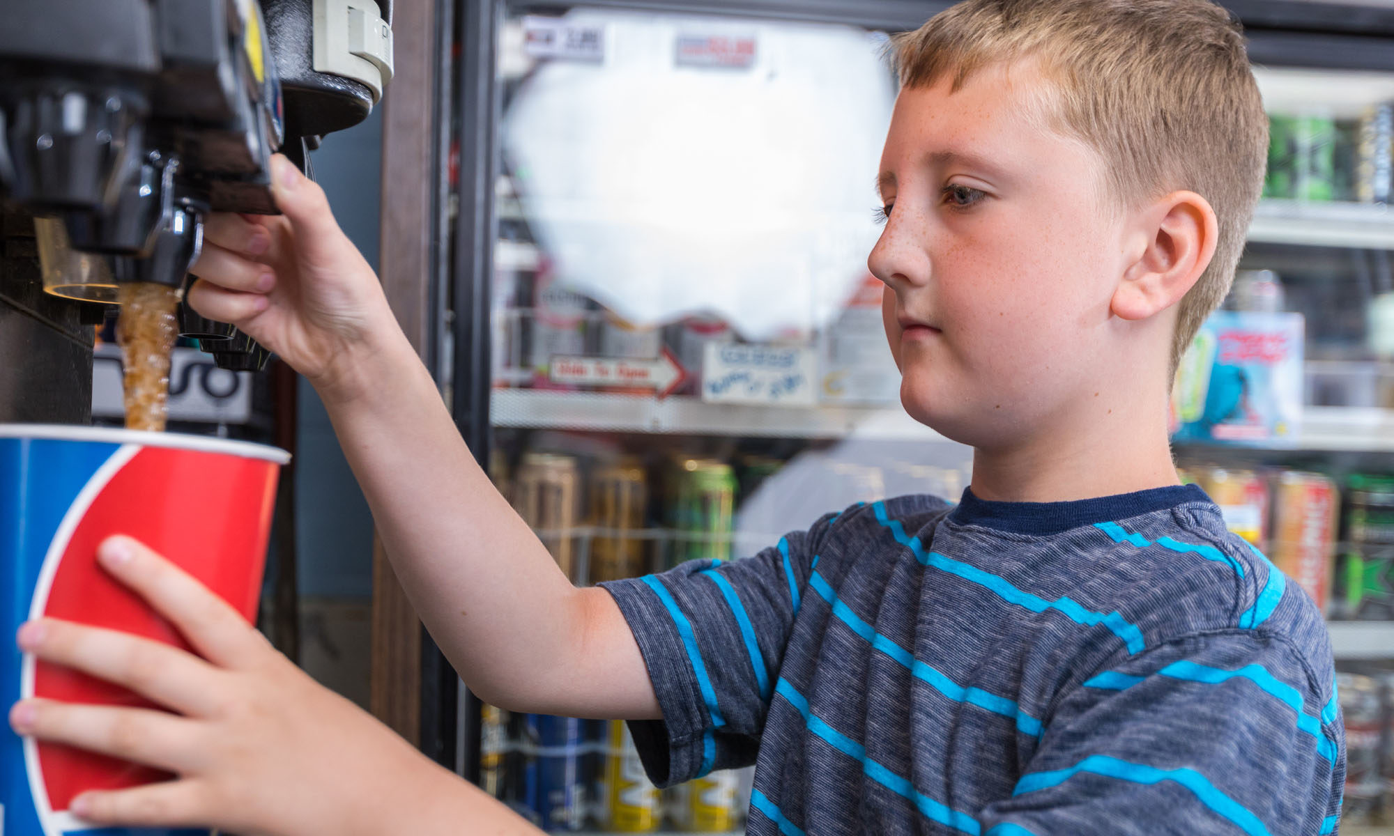 white male kid filling very large soda inside conveinece store